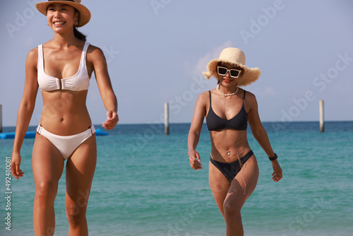 Snapshot sexy tanned woman walk reaxation on tropical beach, Two woman in swimsuits walk along the beach photo