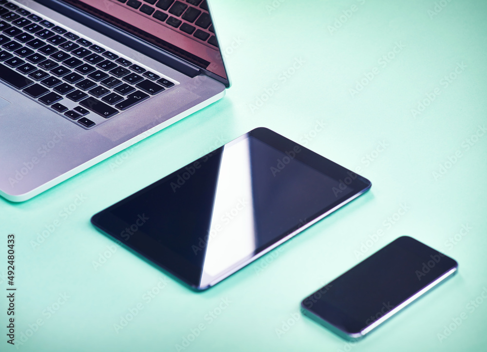 Sleek modern technology. Studio shot of a laptop, tablet and smartphone on a green background. Sleek modern technology. Studio shot of a laptop, tablet and smartphone on a green background.