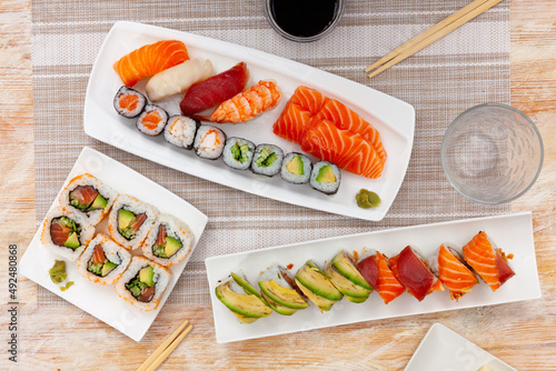 Set of assorted sushi (maki, uramaki, nigiri and sashimi) on white plates, Japanese cuisine