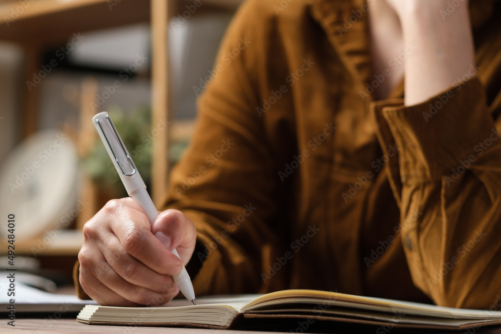 close uop woman hand writing on notebook at worknig desk at home