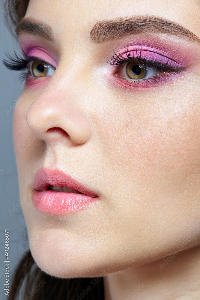Closeup shot of human female face with pink makeup.