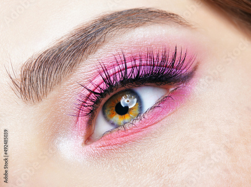 Closeup macro shot of human female eye with pink eyes shadows photo