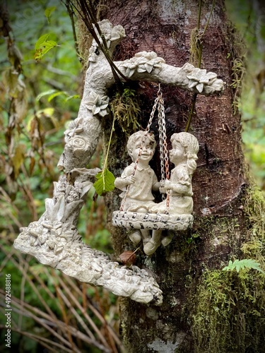 Ceramic boy and girl figure hanging on a tree in the forest