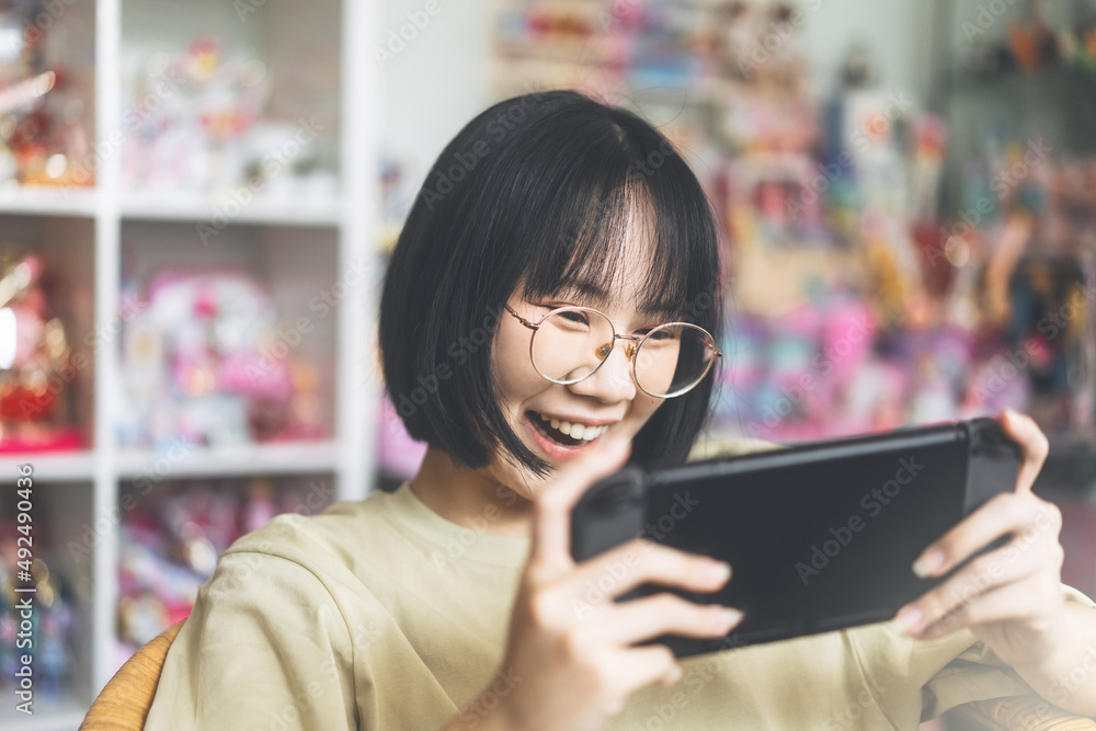 Nerd style happy young adult asian gamer woman wear eyeglasses play a online game Nerd style happy young adult asian gamer woman wear eyeglasses play a online game