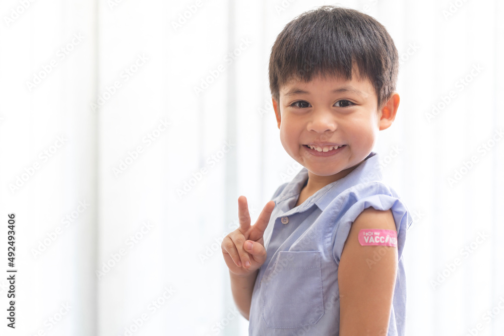 Portrait of happy smile vaccinated little asian kid boy children ages 5 to 11 years old posing show arm with medical plaster after Injection vaccine Covid-19 protection.coronavirus vaccination kid Portrait of happy smile vaccinated little asian kid boy children ages 5 to 11 years old posing show arm with medical plaster after Injection vaccine Covid-19 protection.coronavirus vaccination kid
