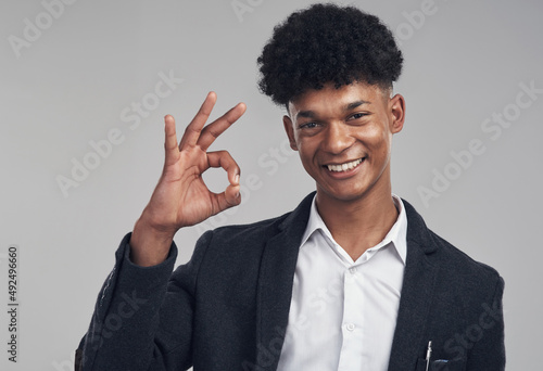 Counting down to success in three...two...one. Studio shot of a young businessman showing an okay hand gesture against a grey background.