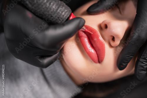 Obraz na płótnie Close-up of swollen female lips during the application of permanent makeup
