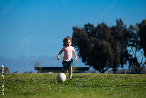 Soccer kids, child boy play football outdoor. Young boy with soccer ball doing kick. Football soccer players in motion. Cute boy in sport action. Kids training soccer.