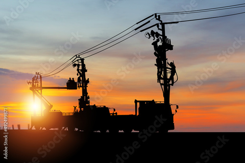 Silhouette of Electrician officer climbs a pole and uses a cable car to maintain a high voltage line system, Shadow of Electrician lineman repairman worker at climbing work on electric post power pole