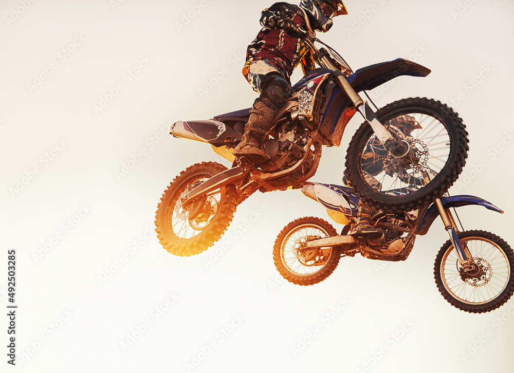 Theyre neck-a-neck. A shot of two motocross riders in midair during a race. - obrazy, fototapety, plakaty 