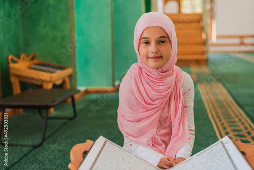 Photography Child girl reading a holy book Quran in the mosque.