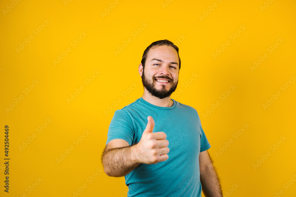 portrait of young hispanic man with copy space and thumbs up on yellow background in Mexico Latin America portrait of young hispanic man with copy space and thumbs up on yellow background in Mexico Latin America