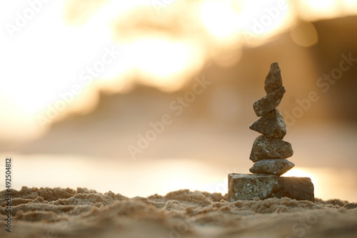 Rock tower on sandy beach in rays of setting sun  selective focus