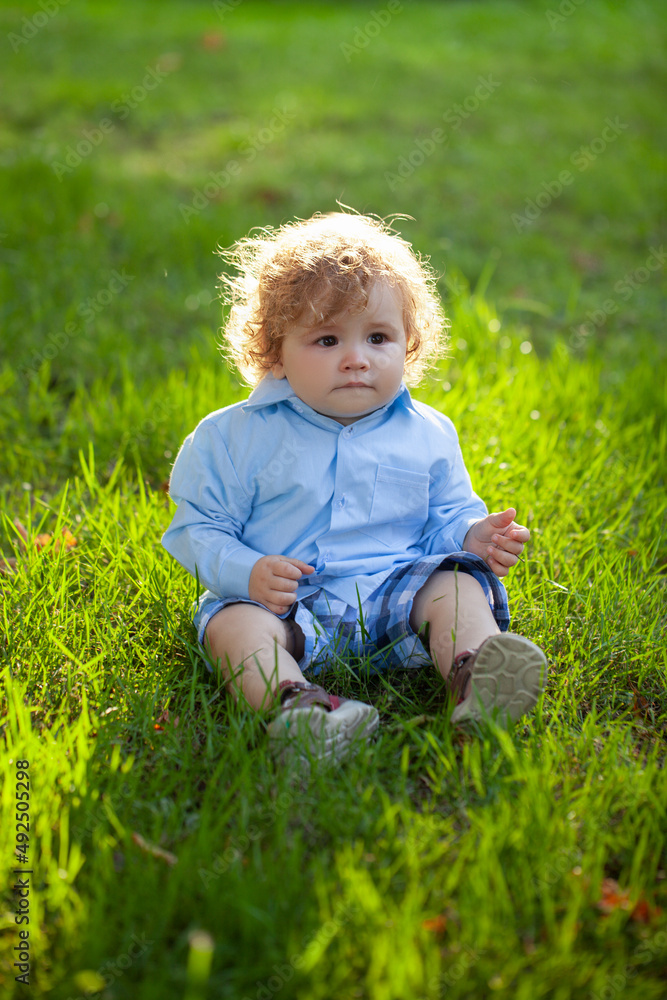 Portrait of a little baby boy sitting on grass playing outdoor in the grass. Portrait of a little baby boy sitting on grass playing outdoor in the grass.