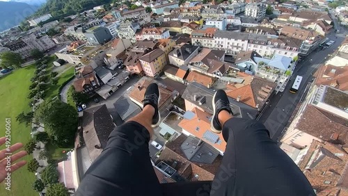 POV action camera shot of a man flying paragliding tandem. Tourist activity over town in Switzerland and landing safely on the ground.