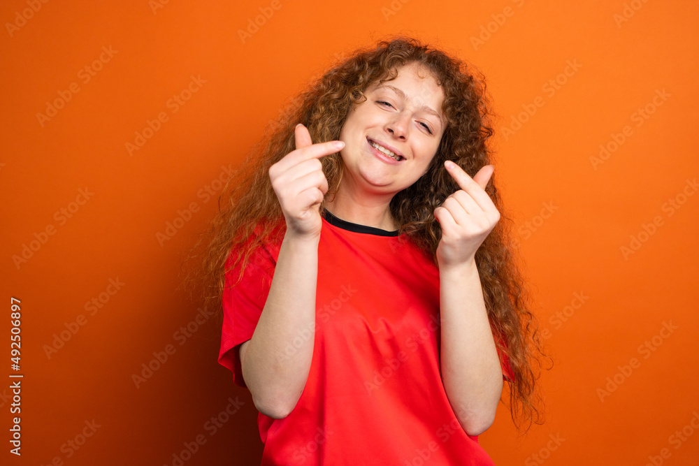 Joyful beautiful redhead woman in red t-shirt keeping her fingers crossed as a luck for football team in the championship. Joyful beautiful redhead woman in red t-shirt keeping her fingers crossed as a luck for football team in the championship.