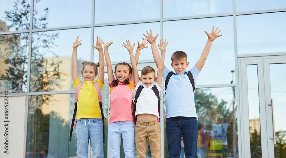 Fototapeta premium Group of children celebrating success near school building