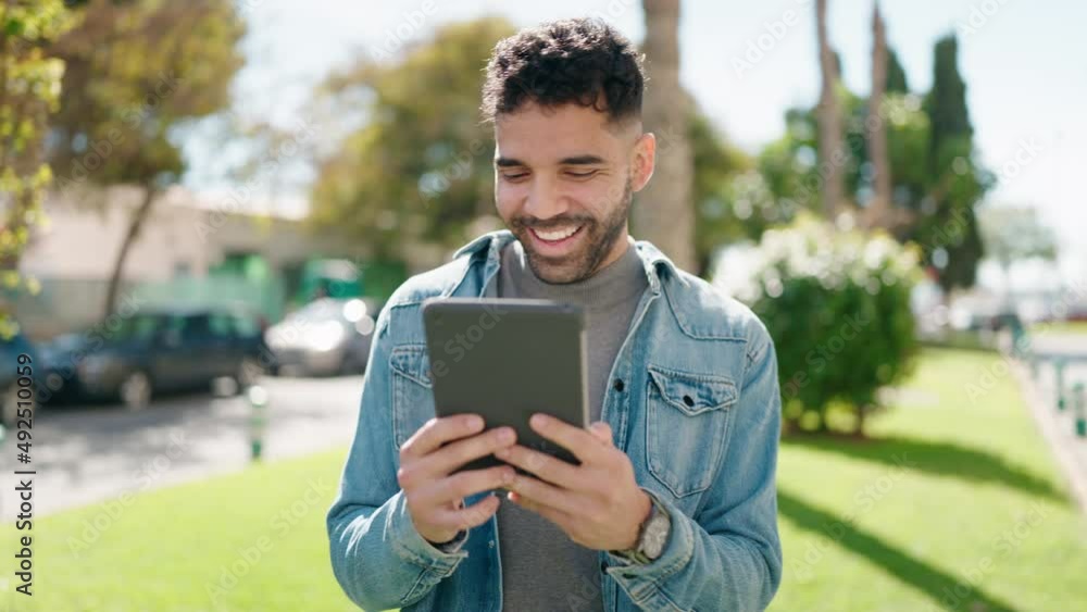 Young arab man watching video by the touchpad at park Young arab man watching video by the touchpad at park