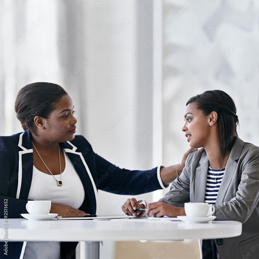 Theyre coworkers and friends. Shot of two coworkers talking together while sitting at a desk in an office. Theyre coworkers and friends. Shot of two coworkers talking together while sitting at a desk in an office.