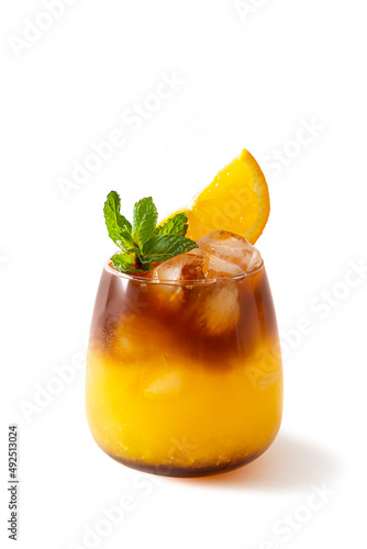 Bumble coffee with ice, mint and a slice of orange isolated on a white background. Espresso, orange juice and syrup in layers in a transparent glass with ice. Summer trendy refreshing coffee drink.