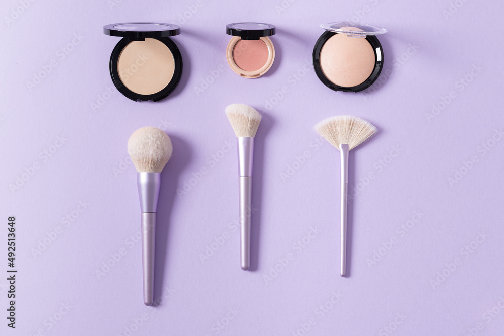 Makeup brushes for blush, highlighter and powder on purple background. Applying of makeup brushes. Cosmetic, professional brushes kit. Flat lay Makeup brushes for blush, highlighter and powder on purple background. Applying of makeup brushes. Cosmetic, professional brushes kit. Flat lay