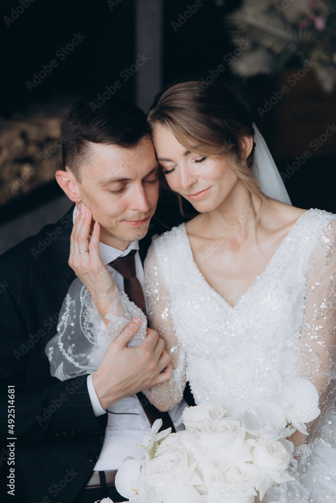 The first meeting of the groom in a black suit and the bride in a white wedding dress with a bouquet in the interior of a photo studio, hotel, on black background
