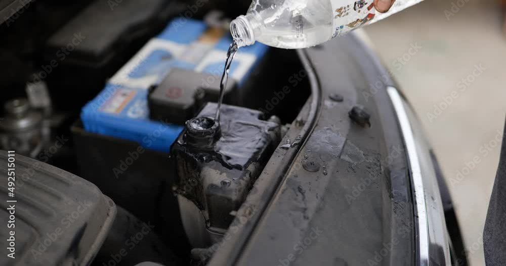 Pouring Water to the car radiator .