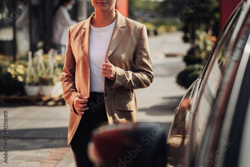 Unrecognisable Stylish Woman in Brown Jacket Moving Near the Car photo