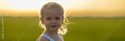 Retrato apaisado de niña de dos años en el campo al atardecer. Brisa veraniega. photo
