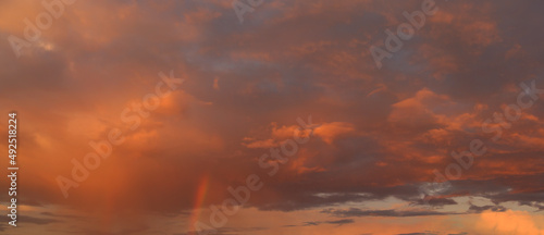 Sunset sky with clouds and rainbow