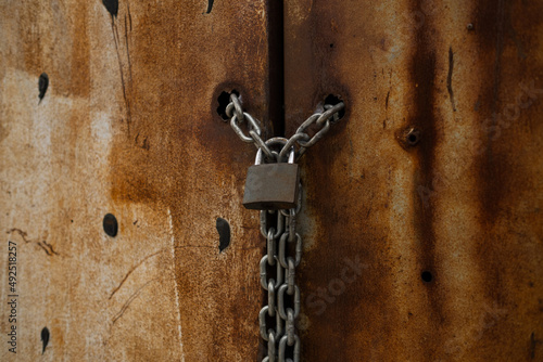 Padlock, the lock of the door of a rusty warehouse, a door bound with a chain and locked on it, close-up door lock © platinumArt
