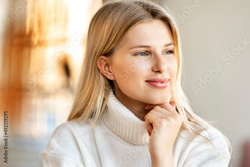 Smiling blond woman with hand on chin photo