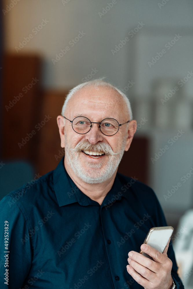 Happy businessman with smart phone in office Happy businessman with smart phone in office