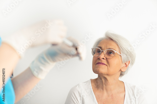 Old gray-haired lady is about to get her vaccine booster to prevent the virus from spreading. High quality photo