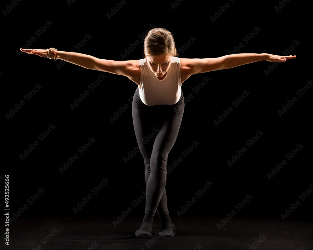 Woman with arms outstretched doing yoga against black background Woman with arms outstretched doing yoga against black background