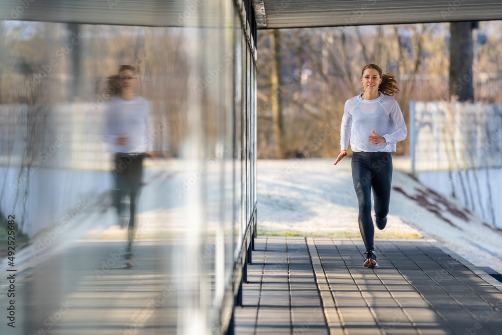 Woman in sports clothing jogging on footpath Woman in sports clothing jogging on footpath