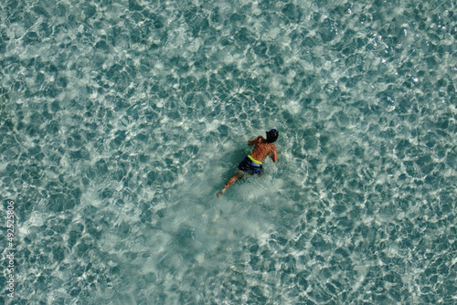 Little kid snorkeling on a turquoise ocean. Aerial view