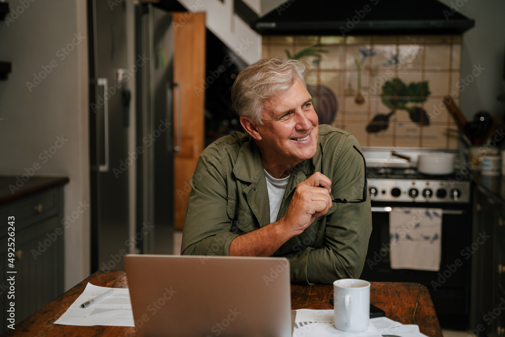 Caucasian senior male working from home smiling to himself