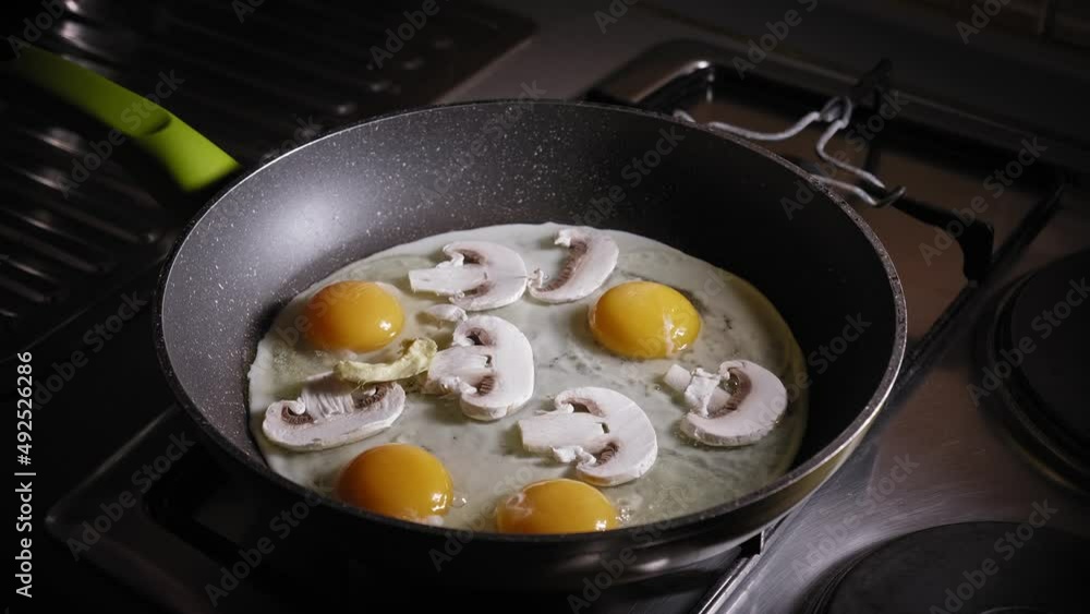 Eggs With Slices Of Mushrooms Cooking In A Pan, Adding Chopped Avocado Fruit. close up Eggs With Slices Of Mushrooms Cooking In A Pan, Adding Chopped Avocado Fruit. close up