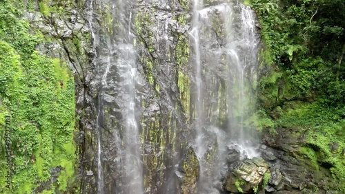 DRONE AERIAL SHOT ZOOMING IN WATERFALL SURROUNDED BY MOSS. photo