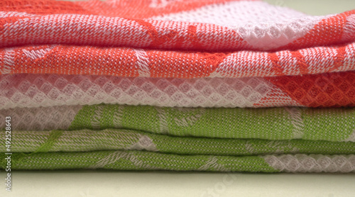 Folded kitchen textile towels of different colors, Household cleaning cloth. Closeup of cleaning rag isolated on a white background.