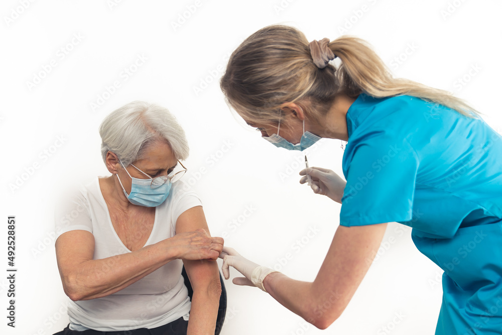 Pensioner woman in her 70s gets a vaccine booster. Copy space. White background. High quality photo Pensioner woman in her 70s gets a vaccine booster. Copy space. White background. High quality photo