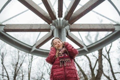 Happy young woman with Down syndrome listening to music in town in winter photo