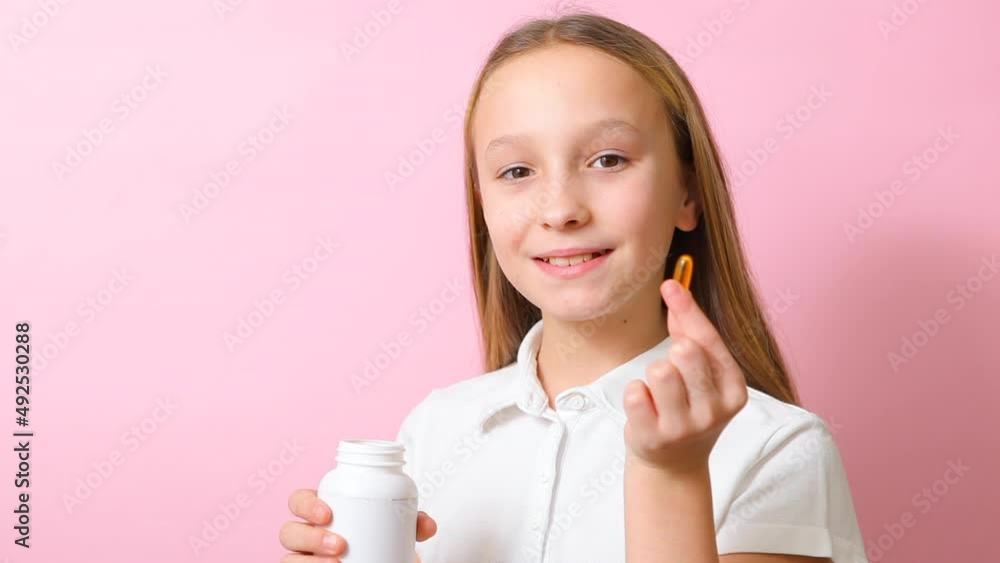 Teenage girl takes omega 3 capsules on a colored background close-up Teenage girl takes omega 3 capsules on a colored background close-up