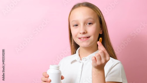 Teenage girl takes omega 3 capsules on a colored background close-up