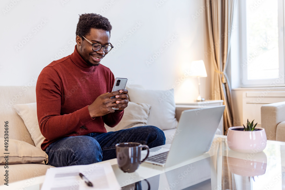 Excited Black African American Man Having a Video Call on Smartphone while Sitting on a Sofa in Living Room. Happy Man Smiling at Home and Talking to His Friends and Family Over the Internet..... Excited Black African American Man Having a Video Call on Smartphone while Sitting on a Sofa in Living Room. Happy Man Smiling at Home and Talking to His Friends and Family Over the Internet.....