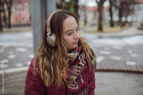 Happy young woman with Down syndrome listening to music in town in winter photo