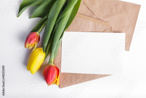 Bunch of tulips and brown craft envelope with empty white card. Top view