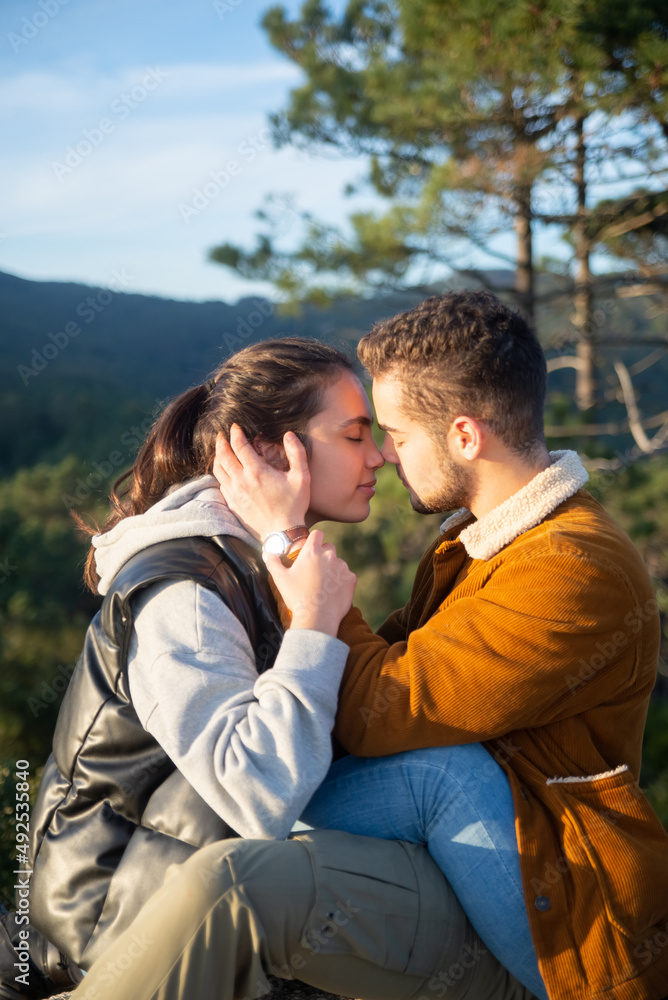 Gentle couple of hikers in autumn. Man and woman in casual clothes sitting at peak, touching with foreheads. Nature, activity, hobby concept Gentle couple of hikers in autumn. Man and woman in casual clothes sitting at peak, touching with foreheads. Nature, activity, hobby concept
