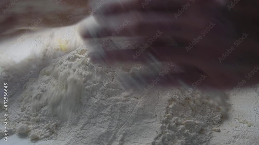 Closeup shot of male hands ff baker kneading dough in flour on wooden table at home. Slow Motion Closeup shot of male hands ff baker kneading dough in flour on wooden table at home. Slow Motion